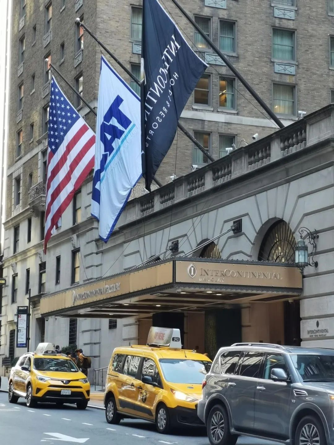 A group of taxi cabs parked in front of a building.